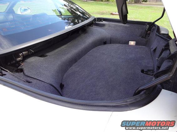 Trunk interior with grey carpet lining and visible hinges