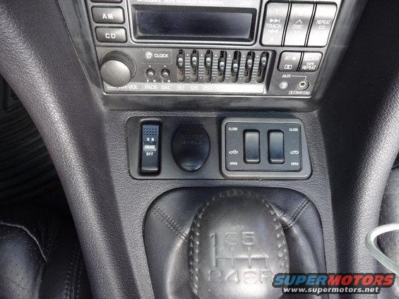 Car interior showing center console with radio, climate controls, gear shift, and cruise control button