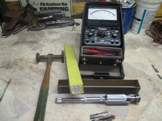 Simpson multimeter, hammer, and drill bits on a floor