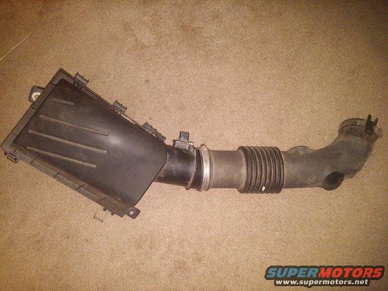 Black plastic air intake hose and filter box assembly on a carpeted surface