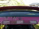 1993 Mazda MX-3 - Rust damage is visible on the rear panel of a maroon car.