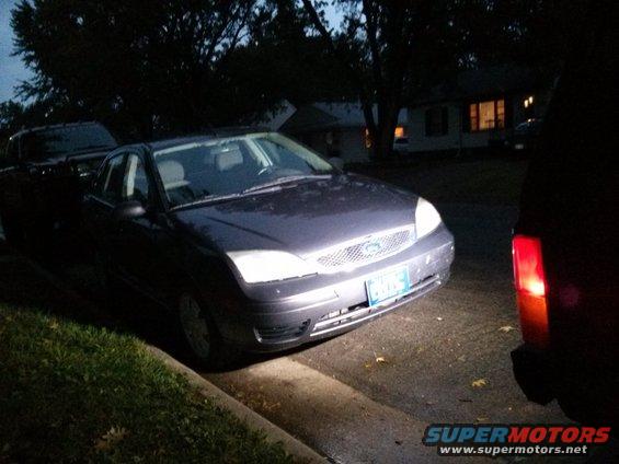 Dark sedan's front grille and headlights illuminated at night