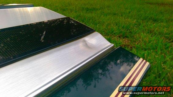 Green tailgate section with red and yellow stripes, brushed metal trim, and a dented silver panel