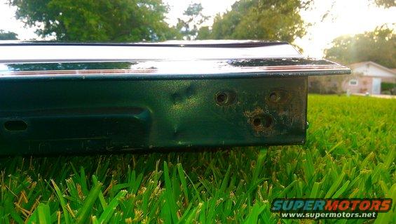 Green tailgate with visible dents and rust spots, resting on grass