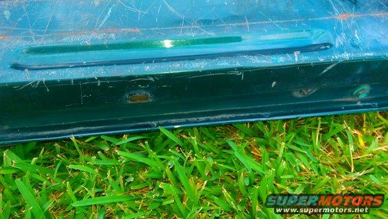 Green tailgate with scratches and a small oval cutout