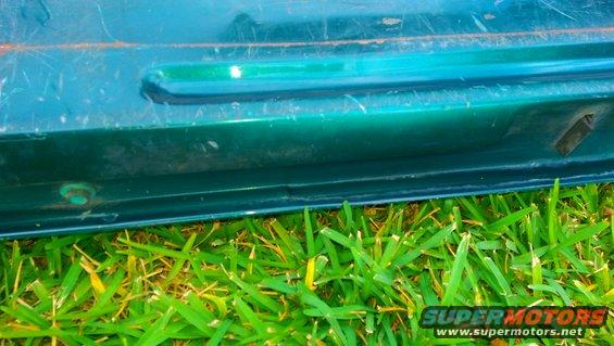 Close-up of a green vehicle's tailgate with grass in the foreground