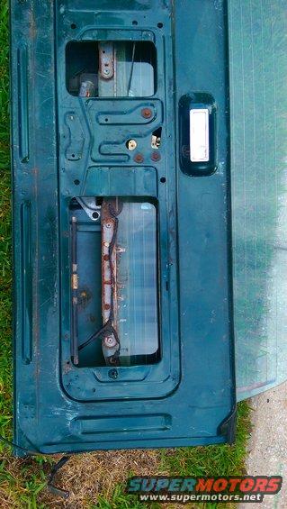 Interior of a dark green Ford Bronco tailgate, showing the mechanism and window frame