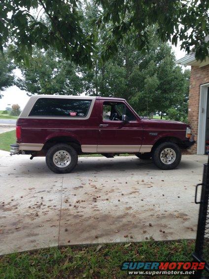 Maroon and tan Ford Bronco with aftermarket wheels parked on a concrete driveway
