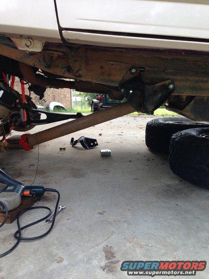 Vehicle underbody with lift kit parts, tools, and tires on concrete