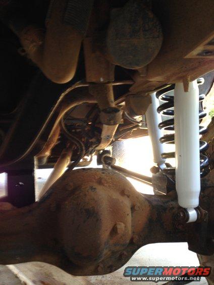 Undercarriage view of white shocks and black springs installed on a vehicle's rear axle