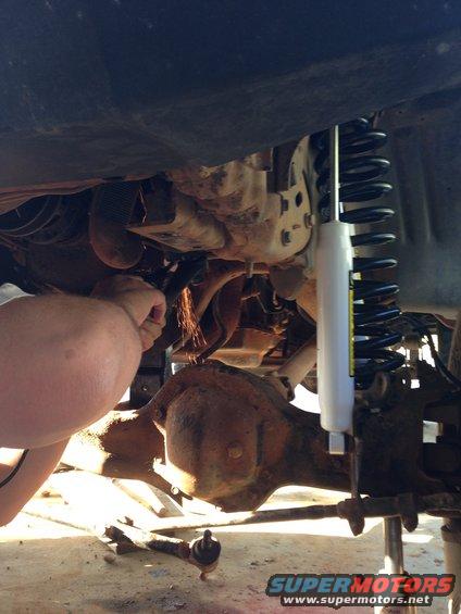 Person grinding on vehicle undercarriage near differential and new shock absorber