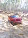 1995 Ford Bronco - A red 1995 Ford Bronco navigates a challenging off-road trail with another vehicle in the distance.