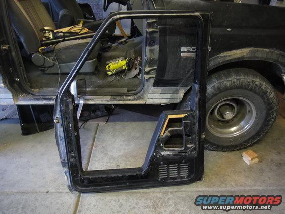 Driver's side door removed from a 1988 Ford Bronco, showing the interior and part of the exterior