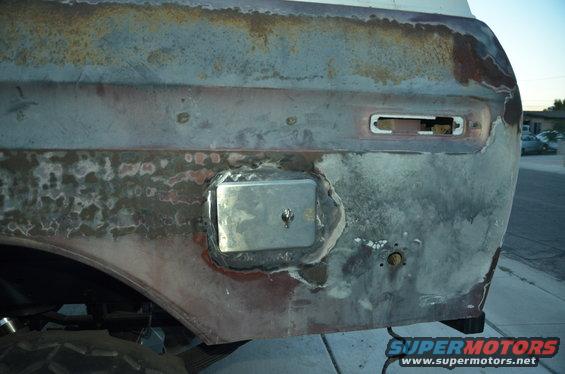 Rusty rear quarter panel with a metal patch and a removed taillight assembly