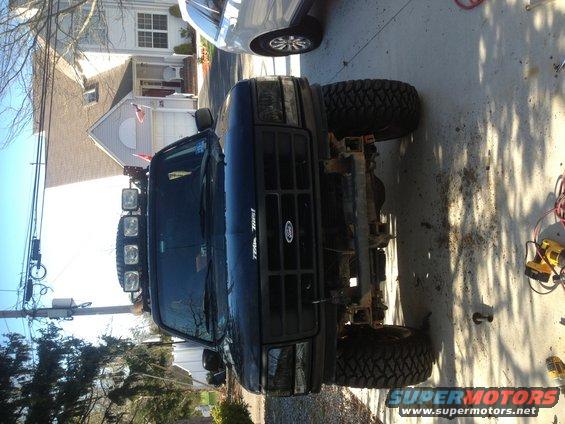 Black Ford Bronco with aftermarket lights on roof, missing front bumper
