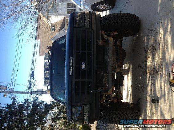 Black Ford truck with aftermarket winch bumper and light bar, lifted suspension, and large off-road tires