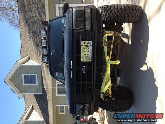 Black Ford truck with aftermarket winch bumper, off-road tires, and light bar