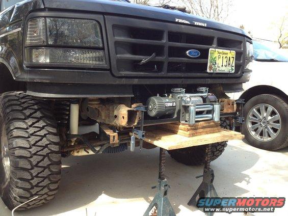 Black Ford truck front end, lifted, with a winch mounted below the grille. New Jersey license plate visible