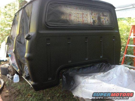 1971 Ford F-250 truck bed covered in plastic and being painted dark green