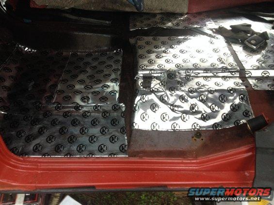 Red truck interior floor with silver sound deadening material covering the driver and passenger sides
