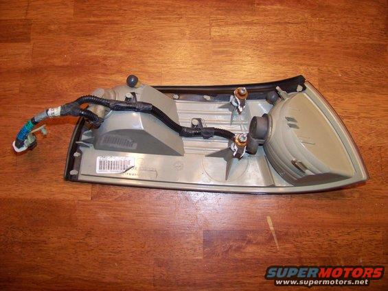 Car tail light assembly with wiring harness, showing internal bulb sockets and a barcode label