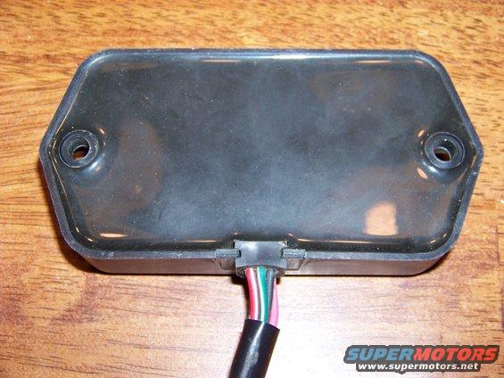 Black electronic part with a wire harness, mounted on a wooden surface