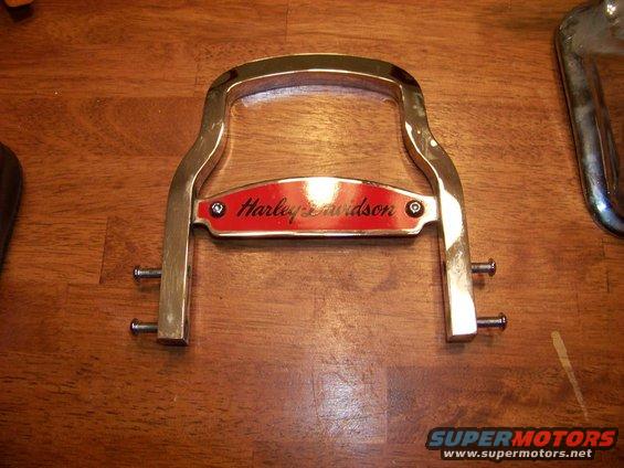 Chrome luggage rack with red Harley-Davidson emblem, on wooden surface