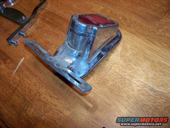 Chrome tail light assembly with red lens on wooden surface
