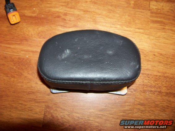Black leather headrest with metal mounting brackets on a wooden surface