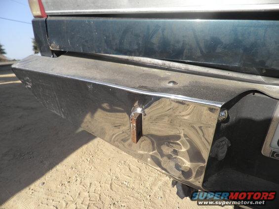 Close-up of a truck's chrome rear bumper with a rusty bracket welded on