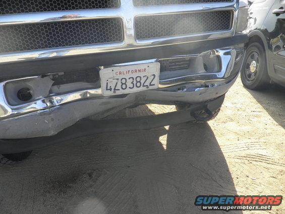 Front of a truck with a bent chrome bumper and California license plate 4Z83822. Another vehicle is partially visible on the right
