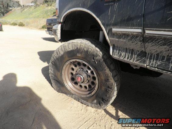 Flat tire on a dark-colored truck with mud splatter