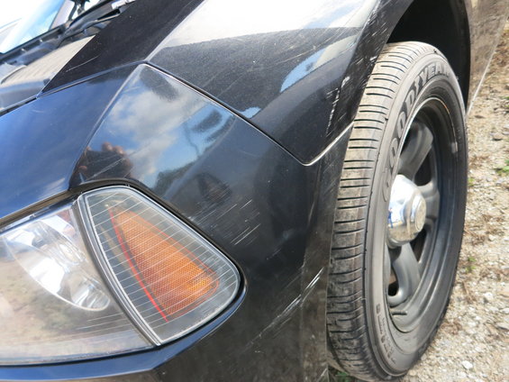 Black car fender with scratches and a Goodyear tire