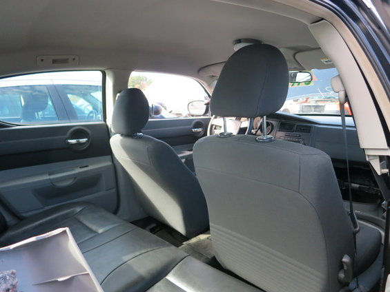 Interior view of a car showing front and back seats, dashboard, and windows. Another car is visible through the window