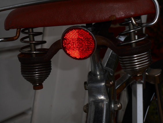 Red bicycle saddle with chrome springs and a red reflector on the seat post