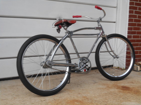 Chrome cruiser bicycle with red handlebars and seat, side view