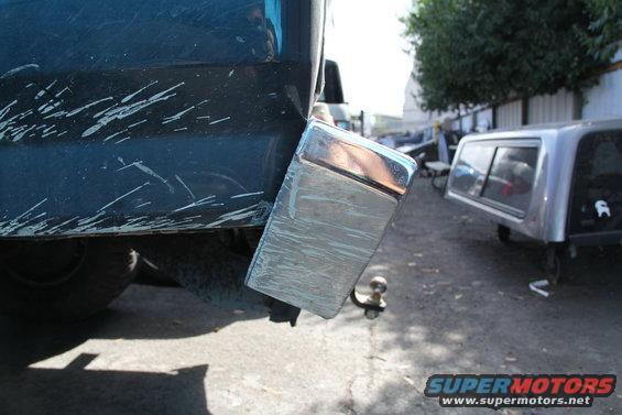 Rear bumper with tow hitch on dark blue truck, other vehicles in background