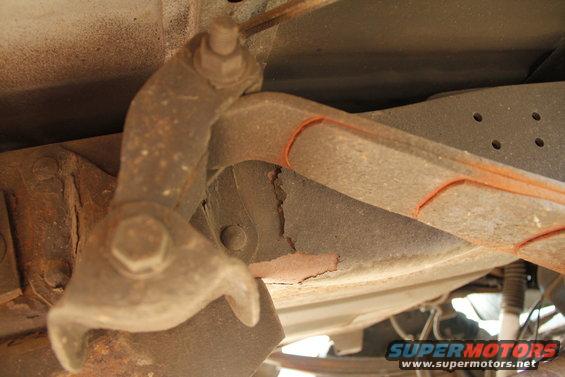 Close-up of rusty underbody suspension component with orange markings