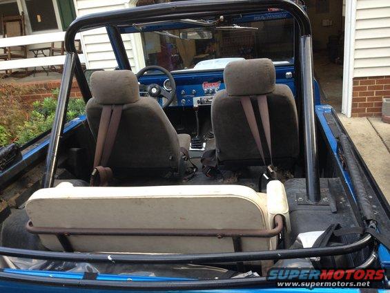 1974 Ford Bronco interior showing front seats, rear bench, roll cage, and dashboard