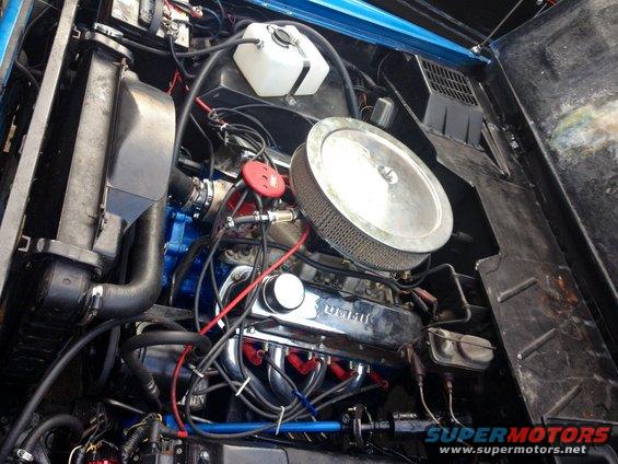 Engine bay with chrome valve covers and air filter. Blue painted block and radiator visible