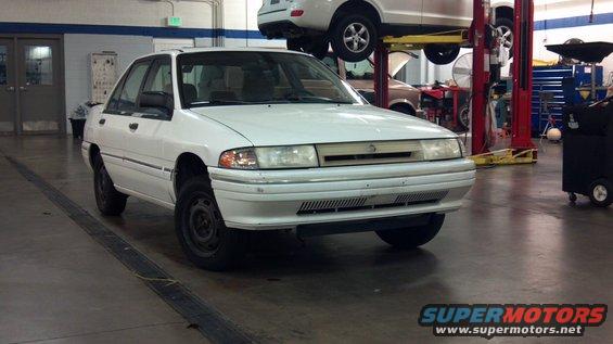 1993 Mercury Tracer sedan parked in a garage with another vehicle on a lift above it