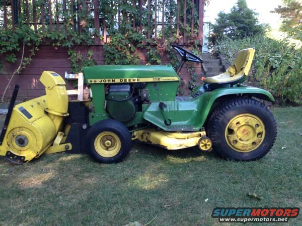 John Deere 112 lawn tractor with a yellow snow blower attachment on the left side