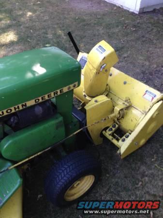 Green John Deere tractor with yellow snow blower attachment, viewed from the side