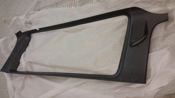 Black plastic interior trim piece with a large rectangular opening and a smaller angled cutout