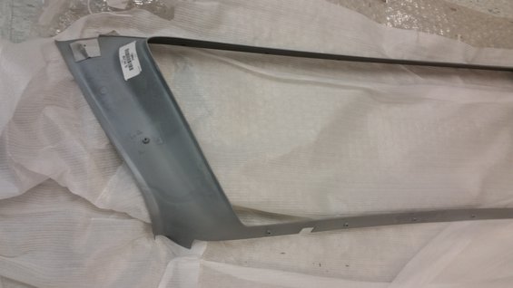 Gray automotive trim piece with a label, wrapped in white material