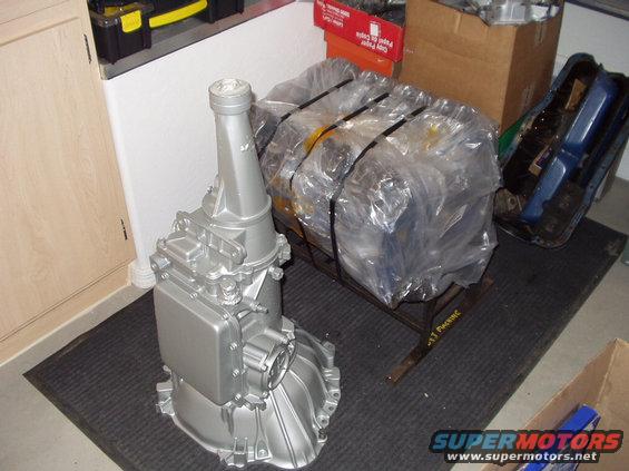 Silver automatic transmission in foreground, engine block wrapped in plastic in background