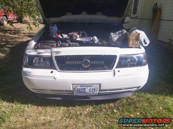 White 2000 Mercury Grand Marquis front view, hood open, engine bay cluttered with tools and parts