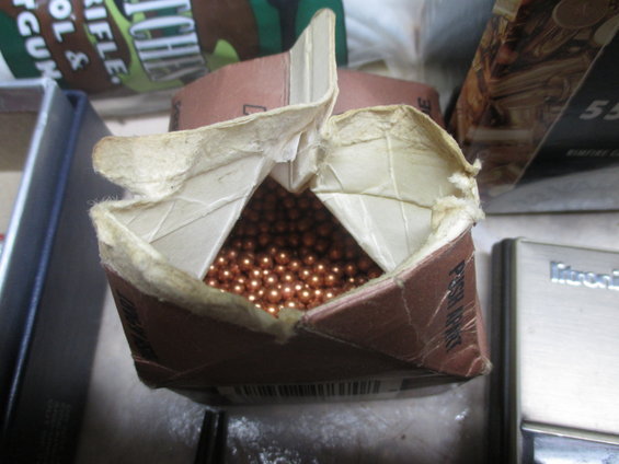 Open cardboard box filled with BBs, next to a silver device with "Mitronix" visible