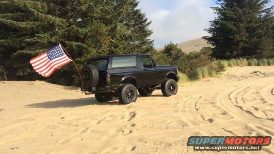 Black 1992 Ford Bronco with American flag on rear tire mount, seen from rear