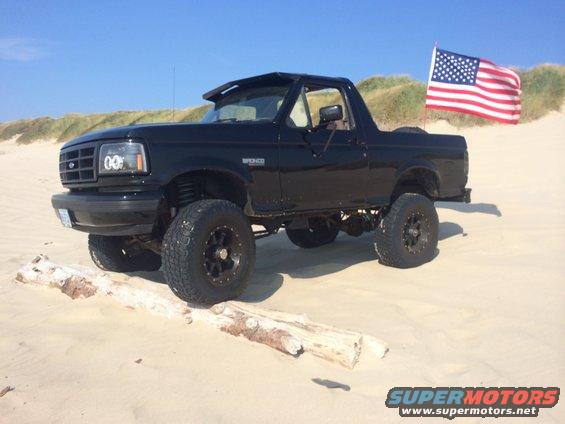 Black 1992 Ford Bronco on sand with American flag